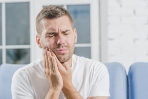 male holding side of mouth in pain experiencing a dental emergency image
